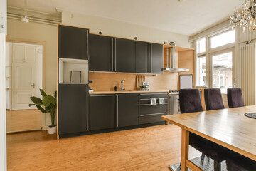 a kitchen and dining area in a house with wood floors, black cabinets, white walls and wooden flooring