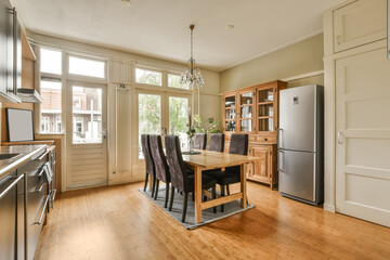 a kitchen and dining area in a house with wood flooring, white walls and doors open to the outside