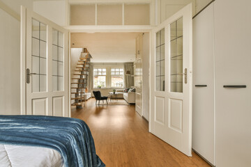 a bedroom with a bed, desk and bookshels on the wall behind it is an open door that leads to...