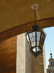 Lantern with warm light on facade of building downtown in Toledo, Spain. Retro street lamp lighting. Vertical photo