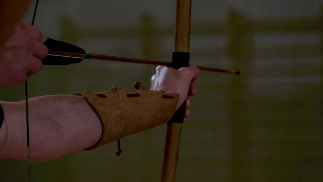 archer tends yew wood bow to shoot an arrow
