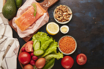 Ketogenic, Paleo, FODMAP, diet concept. Fruits,vegetables, smoked salmon, greens on wooden black sutface.