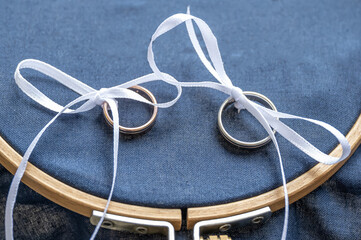 Close-up view of golden wedding rings on blank decorative stiching ring pillow