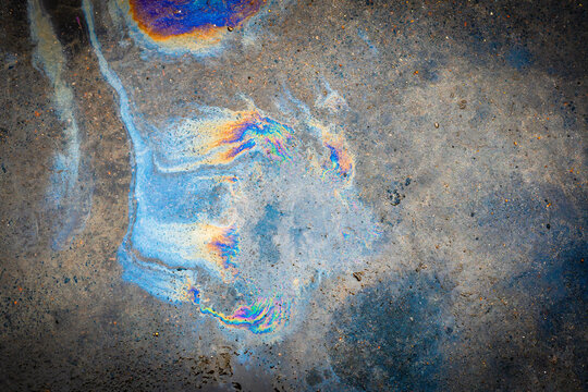 Oil spill on asphalt in the form of a stain. Abstract background from motor oil, gas or petrol spilled on asphalt.