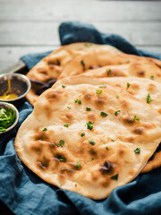 Fresh naan bread on dark wooden background with copy space. Several perfect naan flatbreads on blue linen napkin. Vertical