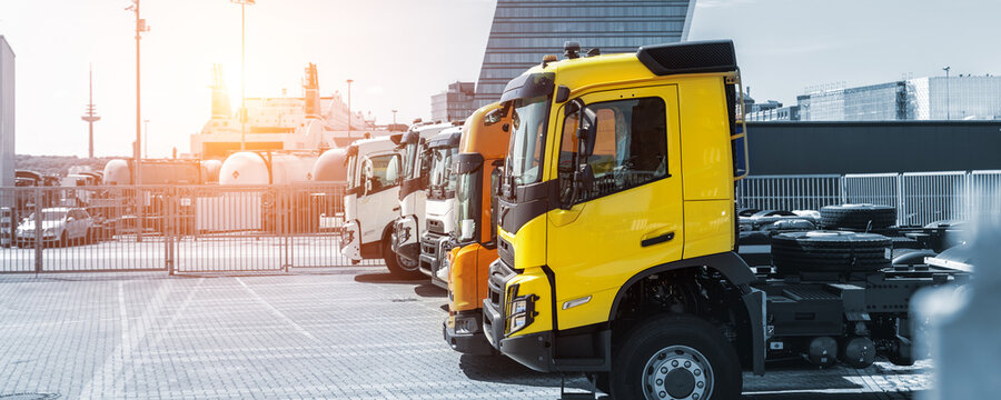 Side View Many New Heavy Commercial Cargo Transport Vehicles Stand At Port For Export Import Shipping In Germany. Modern Semi-trailer Business Industry Truck Tractor Chassis Sale Sea Logistics