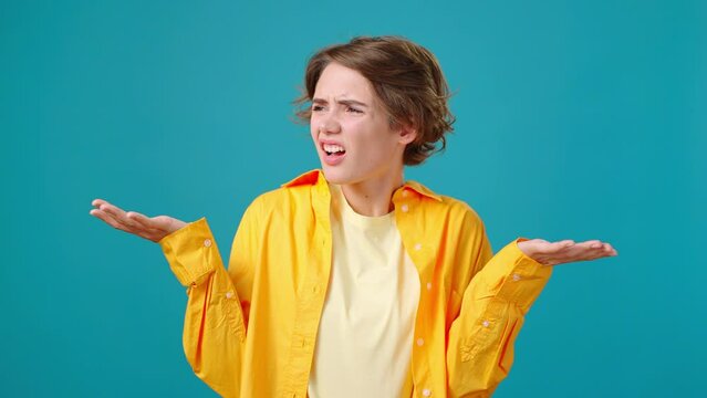 Confused woman grimaces and spreads hands questioningly