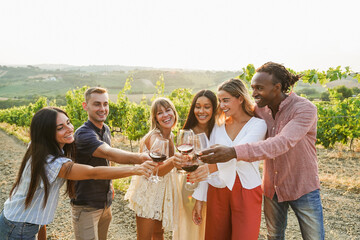 Happy friends cheering with red wine at countryside summer event - Multiracial people having fun during food tour vacation - Travel, holidays and traditional products taste concept - Focus on faces