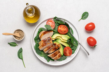 BBQ chicken fillet with spinach salad, tomatoes and avocado. Healthy food top view on white background