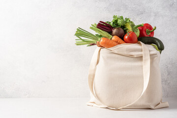 Harvest of organic farm products in cotton bag on white background with copy space. Grocery...