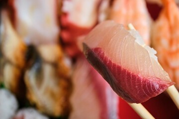 Yellowtail nigiri on a selection of varied Japanese sushi with prawn, octopus, eel, tuna maki.