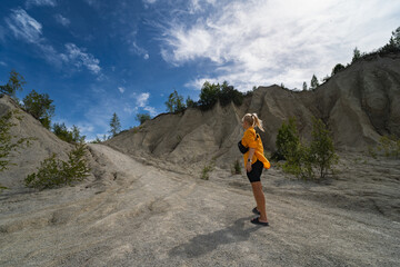 A young girl walks in nature in the summer along the road between the slides at the Rummu quarry on...