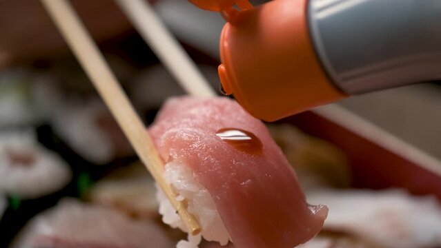 Adding soy sauce on tuna nigiri on a selection of varied Japanese sushi.