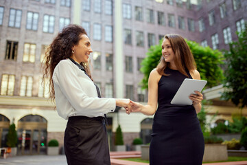 Deal. Business women, colleagues standing outside the office on the street, shaking hands. Partnership and cooperation. Concept of business, career development, ambitions, success, office lifestyle