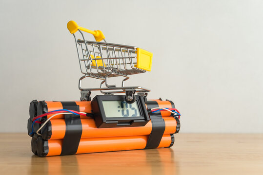 Shopping trolley on time bomb white wall background. Economic recession crisis, inflation rise, core retail sales decrease, goods price up, consumer confidence and consumer price index CPI decrease.