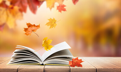 open book in the park on a wooden table with falling autumn leaves and copy space
