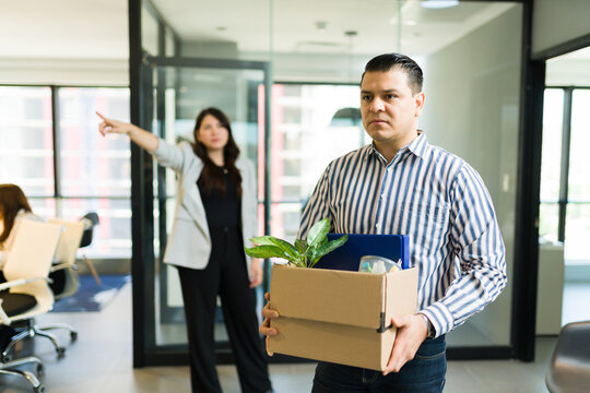 Sad mid adult male employee being dismissed by angry boss in office