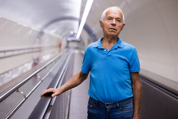 Retired man walking down the escalator to metro station