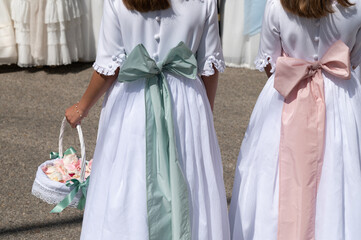 Dos niñas de primera comunión caminan con sus vestidos blancos con lazos.