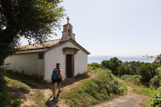 Una senderista camina por un sendero hacia una peque&ntilde;a ermita en Galicia, Espa&ntilde;a.