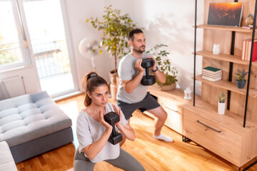 Couple doing squats using dumbbells
