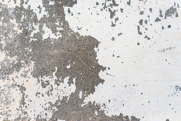 Peeled white paint on an old rough concrete wall. Abstract textured background.