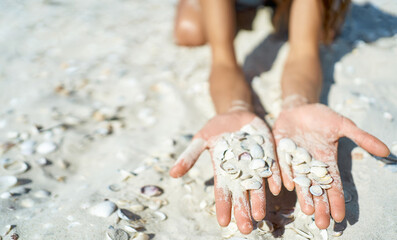 Close-up view of hands holding beautiful seashells on a white sand background. This concept tranquility and serenity that comes with taking care of hands