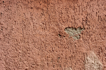 Abstract background. Terracotta colored decorative plaster with damage.