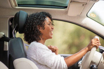 smiling young african american woman driving car