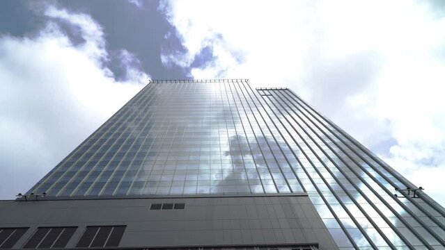 View of high rise glass building and dark steel window system on blue clear sky background.Business concept of future architecture,looking up to the sun light on the top of building