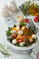 Tuscan Panzanella. Cherry Tomatoes salad with arugula, basil, mozzarella and bread crackers on white bowl. Traditional italian salad. Mediterranean healthy food and cuisine.
