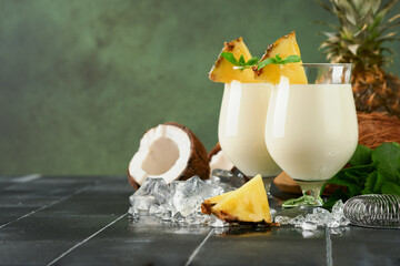 Pina Colada. Traditional caribbean cocktail from rum, pineapple juice and Coconut cream with tropical fruits and bar tools on fresh green background. Summer tropical cocktail and relaxation concept.