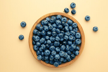 Fresh blueberry in wooden bowl on beige background. Top view. Concept of healthy and dieting eating