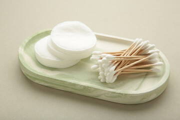 Organic cotton pads and cotton buds for removal makeup on plaster tray on grey background.
