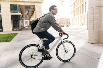 Hipster male freelancer riding to work on a bicycle with a bag, to the office on an eco-transport,...