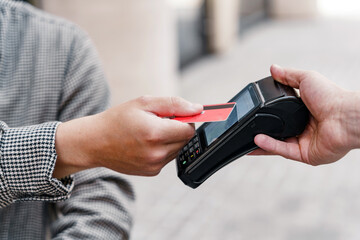 A male customer in a restaurant pays the bill using a plastic bank card, puts it close to NFC, the waiter billed the payment.