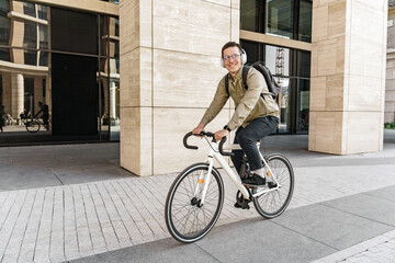 A freelance man riding to work on a bicycle with a bag, to the office on an eco-transport, a...