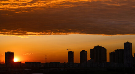 Fototapeta na wymiar City sunset silhouette under dramatic cloud mass
