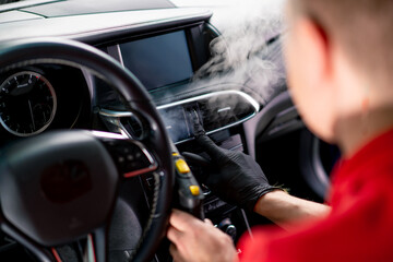 A car wash worker carefully cleans the interior of a luxury car with a rag a brush a vacuum cleaner...