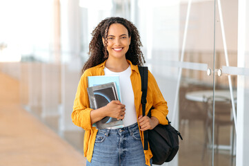 Positive trendy female student. Happy lovely brazilian or hispanic female student, with a backpack,...