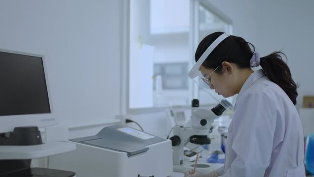 Chemical research scientists use uv visible spectroscopy to check the absorbance and keep the test results in a notebook, Analyze data and collect chemical test results in modern laboratories.