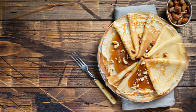 crepes with salted caramel and nuts, top view, wooden background, copy space