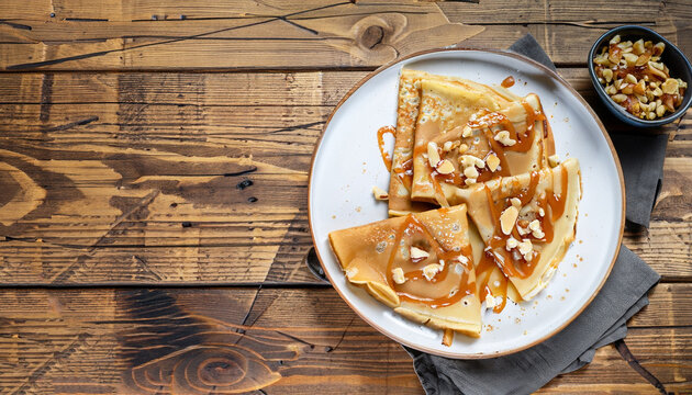 crepes with salted caramel and nuts, top view, wooden background, copy space