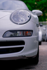 Detail of the bumper and headlight of a white luxury car after being washed at a car service