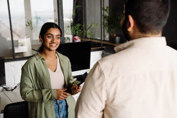 Obraz premium Indian business woman talking with her colleague while standing in office