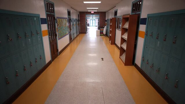 High angle push in down a long empty high school corridor hallway.