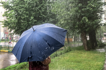 Heavy rain in the Park. Puddles on the sidewalk. Heavy raindrops fall into a puddle on the pavement.  Bubbles on the water from the summer rain. 