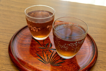 丸い木製のお盆の上に冷たいお茶が入った二つのグラス