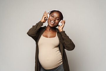 African pregnant happy woman lestening music in headphones