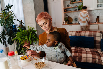 Mature white woman feeding her adopted child at home